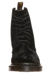 Černé semišové kotníkové boty s kulatou špičkou, s texturovaným povrchem a černými tkaničkami. Silná podešev s mírným podpatkem a poutkem na obouvání.