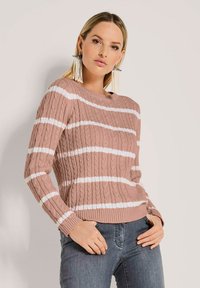 Rosa Kabelstrickpullover mit weißen horizontalen Streifen, Rundhalsausschnitt und gerippten Bündchen. Getragen mit dunklen Jeans.