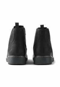 Botas de cuero negro hasta el tobillo con acabado texturizado, detalles de costura, tira de agarre y suela de goma. Presentan un tacón bajo y parte trasera reforzada.