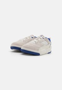 Lys grå semsket sneakers med en pustende mesh-overdel, blå detaljer på hælen og sålen, og hvite snørebånd. Teksturerte gummisåler.