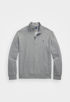 Pelēks adījums puloveris ar ceturtdaļas rāvējslēdzēju, ribotām piedurknēm un apakšmalu. Ar mazu logo uz krūtīm un teksturētu rakstu.