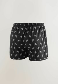 Schwarze Boxer-Shorts mit elastischem Bund, die ein weißes Paisley-Muster aufweisen. Hergestellt aus leichtem Stoff, der eine lockere Passform bietet.