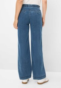 Bredde denimbukser i mørkeblå, med høj talje, stiklommer bagpå og en glat tekstur med en ren kant.