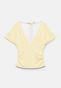 Blouse jaune clair à manches courtes avec col en V profond, côtés froncés et fermeture à nouer dans le dos au niveau de l'encolure.