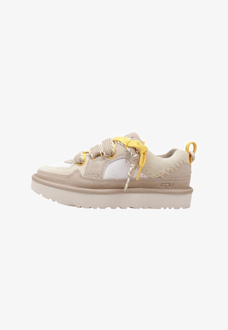 Zapatilla casual de ante beige y blanca con suela gruesa, cordones gruesos en beige y amarillo, y detalles de costura en el talón y los lados.