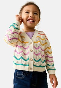 Gebreid vest in crèmekleur met kleurrijke golfpatronen in roze, oranje, paars en turquoise. Voorzien van vijf knopen en geribbelde manchetten.