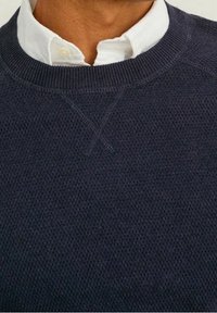 Marinblå stickad tröja med en strukturerad väv, med en rund halsringning och subtila detaljer vid axelsömmarna.