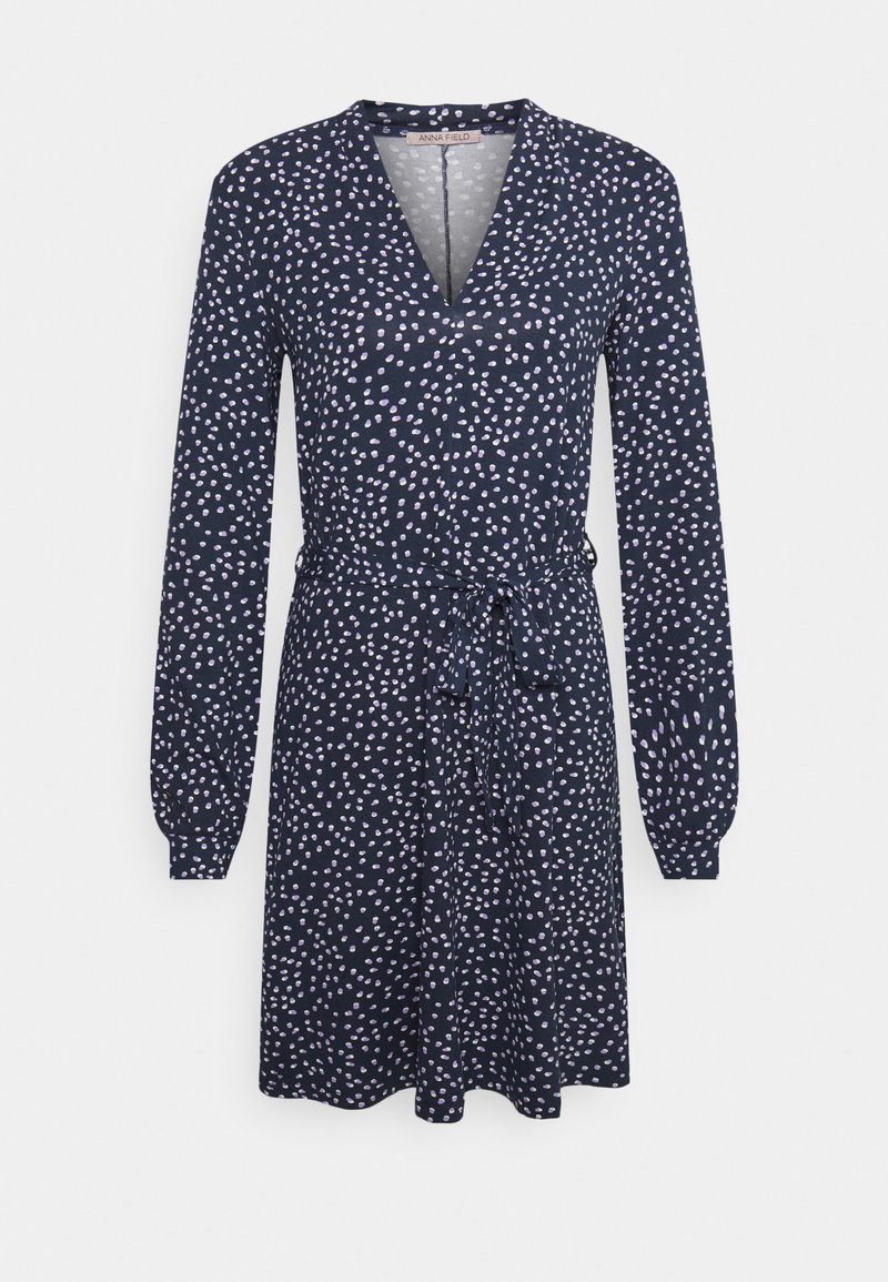 Vestido envolvente azul-marinho com mangas longas, apresentando um cinto na cintura e um padrão de bolinhas em rosa claro. Feito de um tecido suave e texturizado.