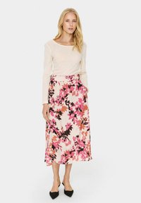 Gėlių rašto sijonas kreminiu atspalviu su rožinėmis ir juodomis detalėmis; ilgo ilgio ir švelnios tekstūros. Derinamas su šviesiu ilgu rankoviniu marškinėliu ir juodais batais.