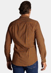 Geruit shirt met een oranje en zwart patroon, lange mouwen, een button-down kraag en een afgeronde zoom. Katoenen stof met een gladde textuur.