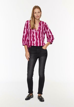Roze en witte geblokte blouse met een V-hals, driekwart mouwen; gecombineerd met zwarte slim-fit jeans en zwarte loafers.