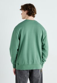 Groene katoenen sweatshirt met een ronde hals en een relaxte pasvorm, voorzien van ribgebreide manchetten en zoom. De achterkant laat een glad, onversierd oppervlak zien.