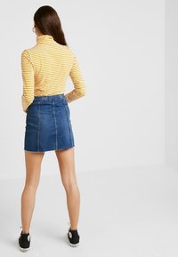 Gulvit randig polotröja kombinerad med en blå jeansmini. Kjolen har en fransig fåll och bakfickor.