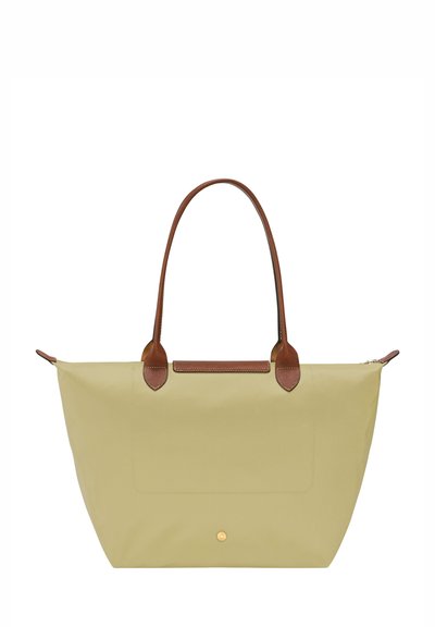 Canvas tote bag in light green with brown leather handles and accents. Features a flat rectangular shape and a subtle front pocket.