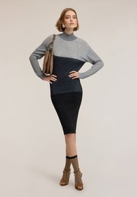 Abito lavorato a maglia con colletto alto, caratterizzato da un design bicolore in grigio e blu scuro, lunghezza a metà polpaccio, finitura testurizzata, abbinato a calze a motivi.