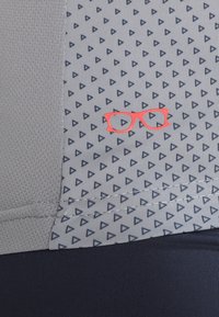 Tela gris con un patrón de pequeños triángulos marinos, con un ícono de gafas rojas exhibido de manera prominente. Textura suave con un acento oscuro en la parte inferior.