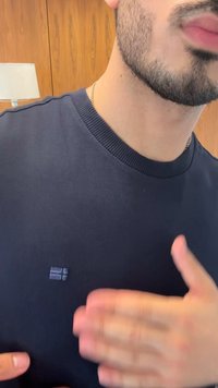Tengerészkék pamut póló, bordázott nyakkivágással és egy kis logóval a mellrészén. Az anyag simának és testhezállónak tűnik.