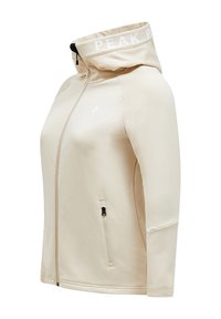 Beige hooded jacket made of soft material. Features a zip pocket on the side, a white logo on the collar, and a fitted design.