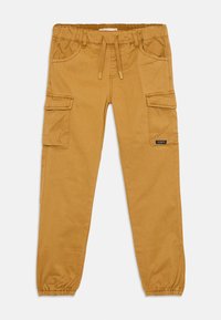 Pantalons cargo marron avec des poignets élastiques, taille à cordon, poches avant et poches latérales à rabat, posés à plat sur un fond blanc.