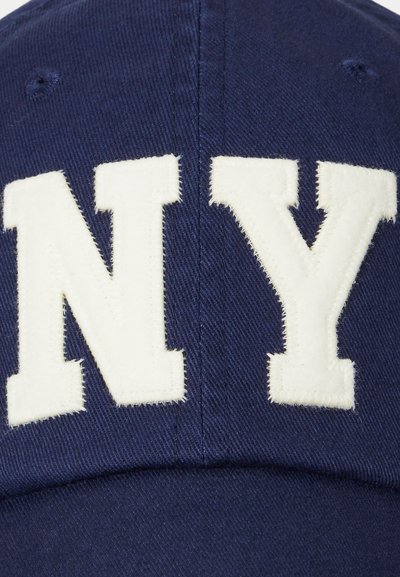 Casquette de baseball bleu marine avec broderie en feutre blanc "NY". Présente un design structuré et un tissu texturé. Visière courbée classique.