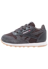 Szary sneaker wykonany z połączenia zamszu i skóry, z siateczkową cholewką, gumową podeszwą i logo Reebok po boku.