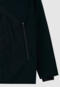 Giacca nera con tasca con zip sul lato sinistro, realizzata in un tessuto liscio con finitura opaca e una vestibilità leggermente ampia.