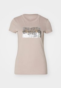 Camiseta de algodón beige con manga corta y cuello redondo, que presenta un diseño rectangular de lentejuelas plateadas con "AIX" en letras doradas.