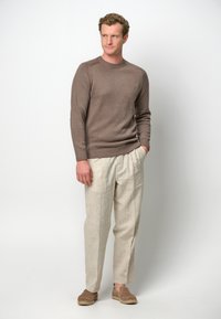 Brauner wollener Rundhalsausschnitt-Pullover, helle beiger Leinenhose und hellbraune Slipper. Das Outfit verfügt über gerippte Bündchen und eine lässige Passform.