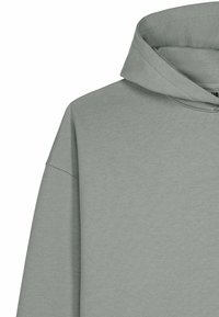 Sweatshirt à capuche gris clair avec coutures visibles sur l'épaule et détails de coutures, présenté sur un fond blanc.
