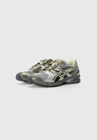 Chaussures de sport avec une tige en mesh gris et noir, présentant des accents réfléchissants et une semelle rembourrée pour un soutien et un confort optimal.
