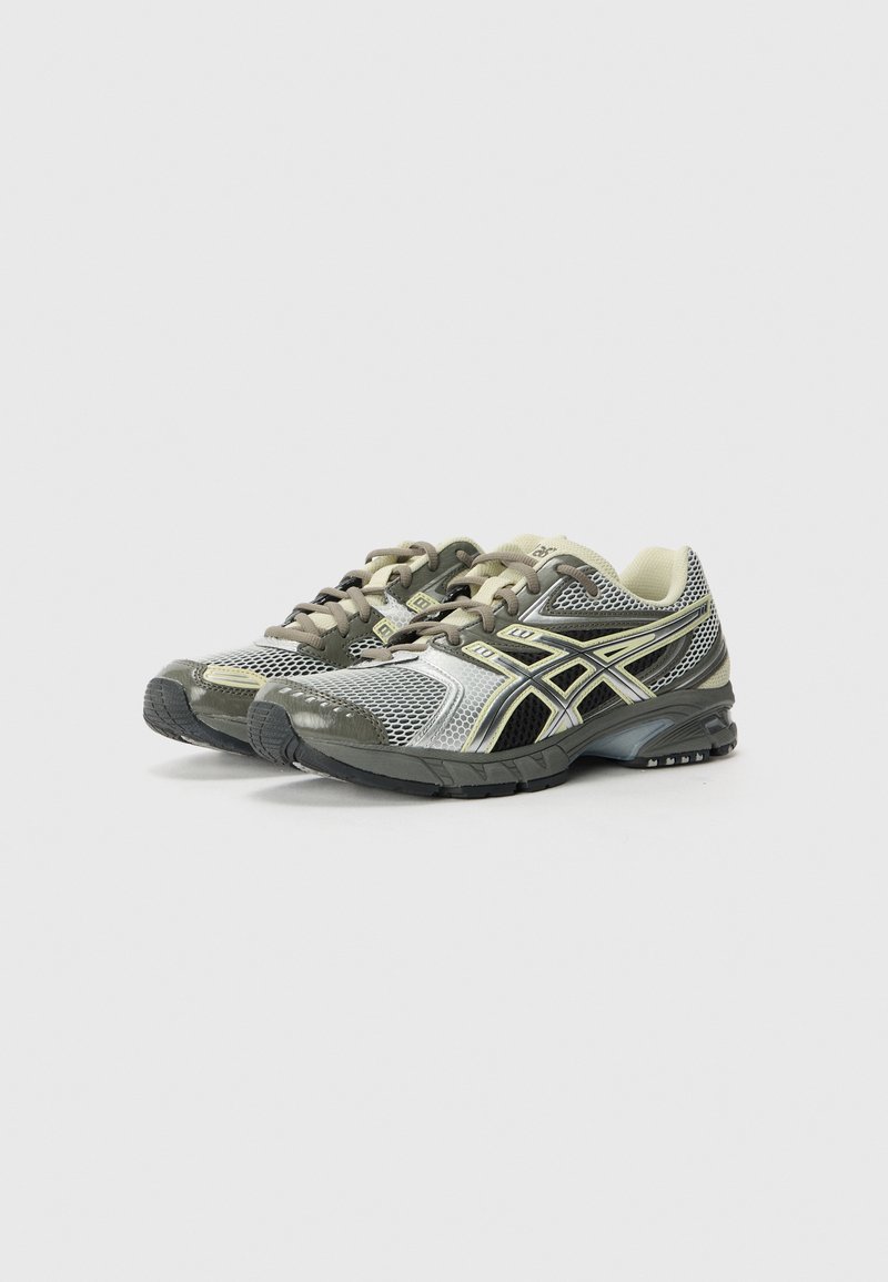 Sportieve schoenen met een bovenwerk van mesh in grijs en zwart, voorzien van reflecterende accenten en een gewatteerde zool voor ondersteuning en comfort.