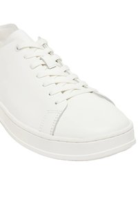 Zapatilla de cuero blanca con punta redondeada, suela plana y cordones en tono similar. Textura suave con costuras mínimas y sin patrones prominentes.