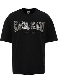 Black cotton t-shirt featuring bold white embroidery of "KARLKANI" and "EST. 1989" in a contrasting design. Short sleeves and a round neckline.