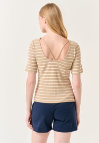 Gestreepte beige top met korte mouwen, voorzien van een lage ronde rug en dunne bandjes. Gepaarde met marineblauwe shorts. Gestructureerde stof.