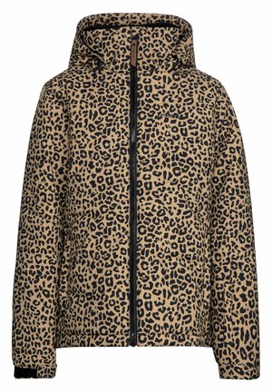 Persona con chaqueta de estampado de leopardo, pantalones rosas y zapatos negros, de pie con una pierna extendida sobre un fondo blanco liso.