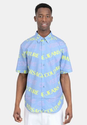 Camicia a maniche corte con bottoni in tessuto azzurro chiaro. Presenta testo multicolore in rosa e giallo, con una vestibilità comoda e colletto a punta.