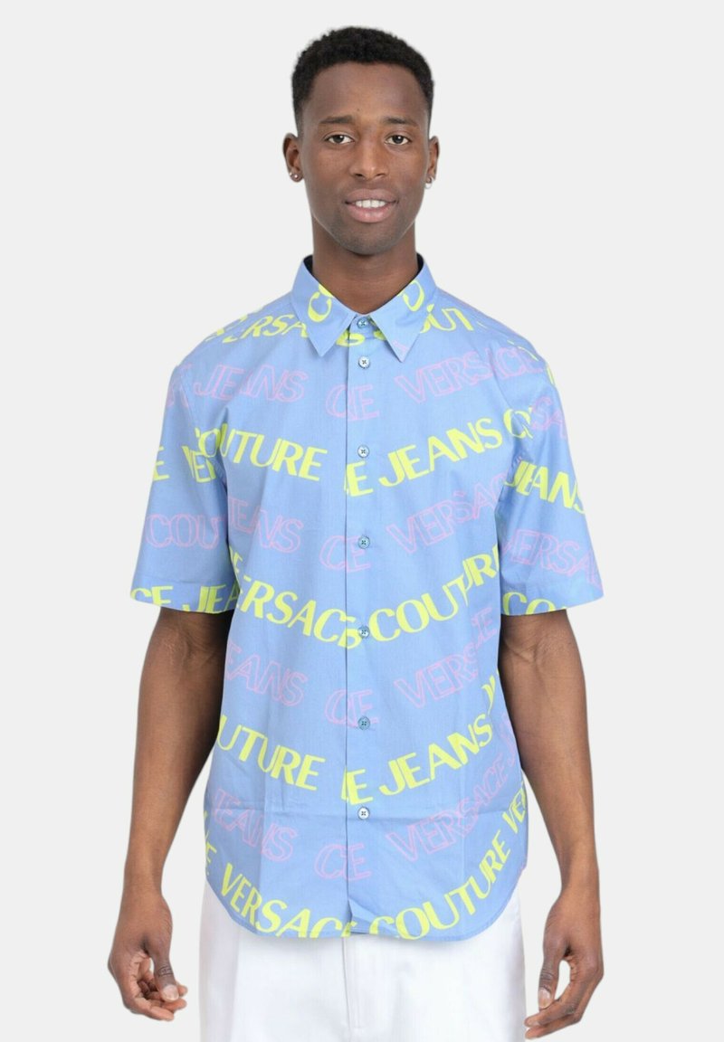 Camicia a maniche corte con bottoni in tessuto azzurro chiaro. Presenta testo multicolore in rosa e giallo, con una vestibilità comoda e colletto a punta.