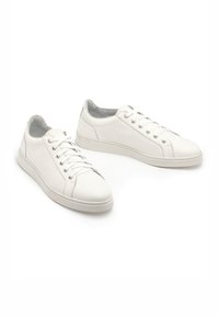 Białe skórzane trampki o gładkim wykończeniu, okrągłym nosku i perforowanych akcentach po bokach. Posiadają sześć oczek i lekko podniesioną podeszwę.