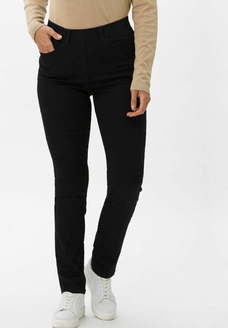 Pantaloni neri slim-fit con una texture liscia, dotati di vita media, tasche frontali e un design elegante, abbinati a sneakers bianche.