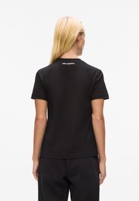 Schwarzes Baumwoll-T-Shirt mit Rundhalsausschnitt und kurzen Ärmeln, mit dem Aufdruck "KARL LAGERFELD" am hinteren Kragen.