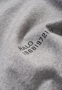 Grauer Stoff mit glatter Textur und schwarzem Drucktext: "HALO 19681972197" in einer fetten, modernen Schriftart.