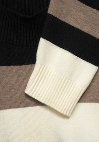 Tröja med horisontella ränder i svart, ljusbrun och creme. Tillverkad av mjukt stickat tyg med ribbade muddar.