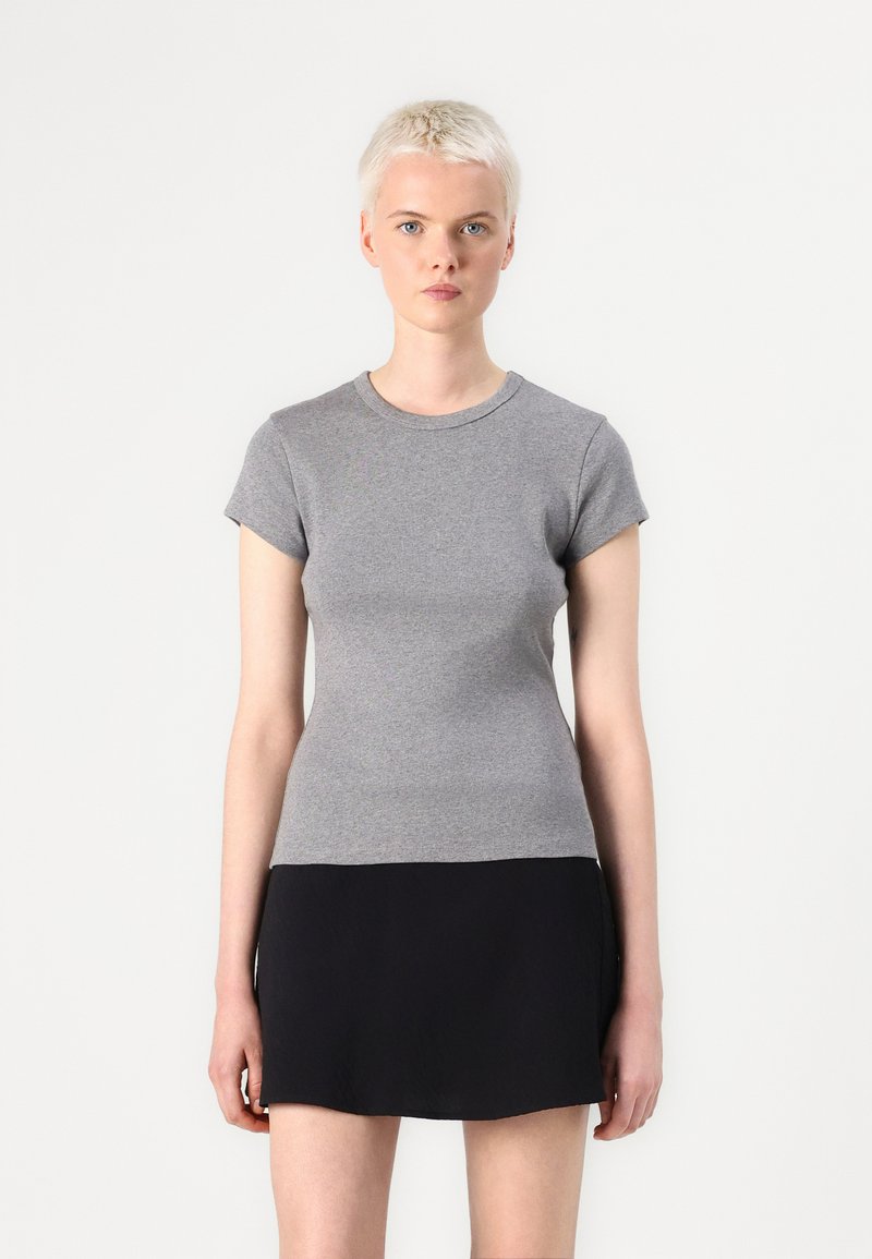 Top grigio a maniche corte realizzato in tessuto leggero, con scollatura rotonda e design aderente, abbinato a una gonna nera elasticizzata.