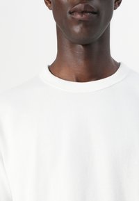 White crewneck sweatshirt made of cotton, featuring a smooth texture and a ribbed neckline, no visible patterns or accents.