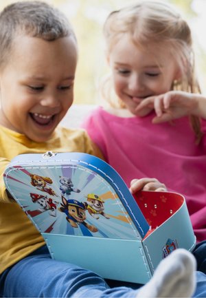 Twee kinderen zitten samen te glimlachen terwijl ze een blauwe speelgoedkist met Paw Patrol-thema openen.