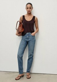 Brown sleeveless top, light blue straight-leg jeans, brown woven handbag. Sandals with a low heel. Minimalist background.