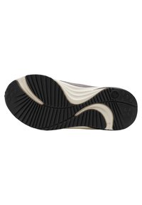 Podeszwa sportowego obuwia z teksturowanej czarnej gumy, z falistą białą wkładką oraz rowkami zwiększającymi przyczepność. Wyraźny krzywy akcent w designie.