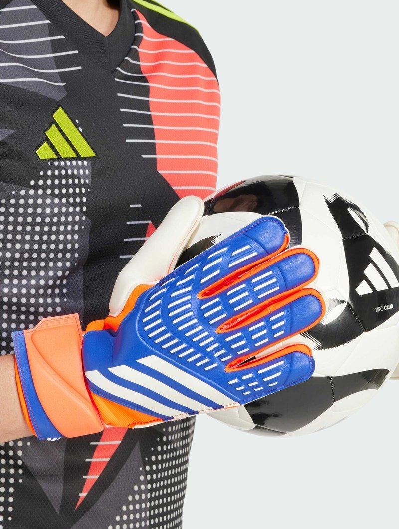Blaue und orange Torwarthandschuhe mit texturiertem Griff und weißen Akzenten, gehalten neben einem schwarz-weißen Fußball mit einem Logo.