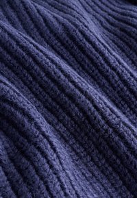 Tamnoplava pletena tkanina s okomitim rebrastim teksturom, s debelim, teksturiranim koncem i blagom runjavošću. Mekan, topao izgled.