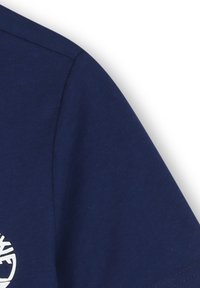 Tessuto blu navy con cucitura visibile e una parte di grafica circolare bianca sul bordo sinistro.